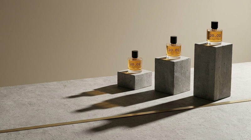 Three 20.O2 perfume bottles standing on concrete plinths of different heights casting long parallel shadows